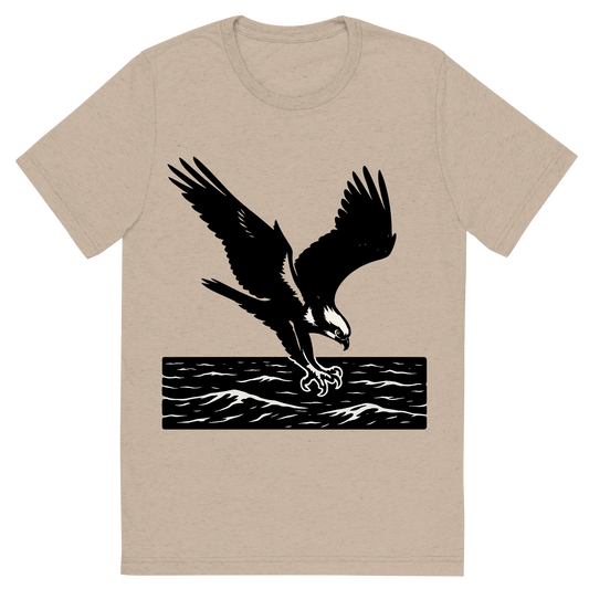 Front view of a Premium Tri-Blend Crew Neck T-Shirt in Tan showing 'A high-contrast silhouette with minimal accent color, powerful graphic of a high-contrast silhouette of an osprey diving with talons extended over the ocean, wings outstretched in dynamic pose, accented with white head markings, transparent background, optimized for dtg printing'