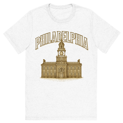 Front view of a Premium Tri-Blend Crew Neck T-Shirt in Solid White showing 'A typographic, nostalgic graphic of a typographic illustration of the words 'philadelphia' with a vintage line art drawing of independence hall'