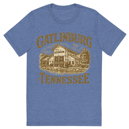 Front view of a Premium Tri-Blend Crew Neck T-Shirt in Blue showing 'A typographic, nostalgic graphic of a typographic illustration of the words 'gatlinburg, tennessee' with a vintage line art drawing of ripley’s aquarium'