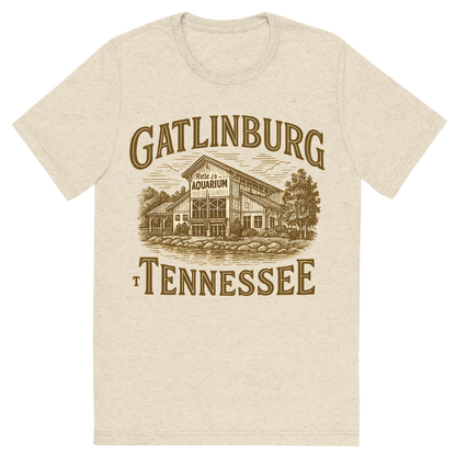 Front view of a Premium Tri-Blend Crew Neck T-Shirt in Oatmeal showing 'A typographic, nostalgic graphic of a typographic illustration of the words 'gatlinburg, tennessee' with a vintage line art drawing of ripley’s aquarium'
