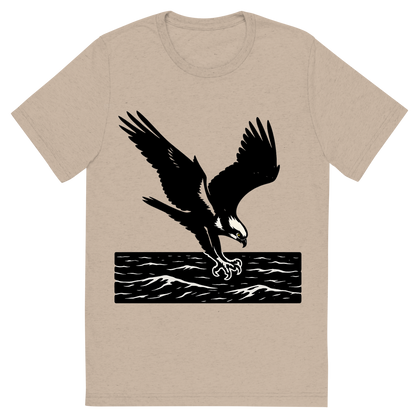 Front view of a Premium Tri-Blend Crew Neck T-Shirt in Tan showing 'A high-contrast silhouette with minimal accent color, powerful graphic of a high-contrast silhouette of an osprey diving with talons extended over the ocean, wings outstretched in dynamic pose, accented with white head markings, transparent background, optimized for dtg printing'