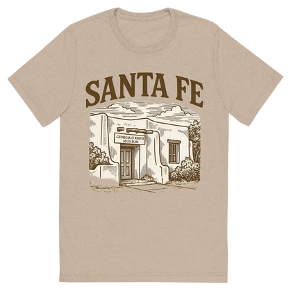 Front view of a Premium Tri-Blend Crew Neck T-Shirt in Tan showing 'A typographic, nostalgic graphic of a typographic illustration of the words 'santa fe' with a vintage line art drawing of the georgia o’keeffe museum'