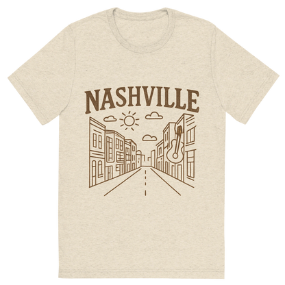 Front view of a Premium Tri-Blend Crew Neck T-Shirt in Oatmeal showing 'A minimalist, playful graphic of a typographic illustration of the words 'nashville' with a vintage line art drawing of broadway street'
