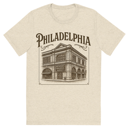 Front view of a Premium Tri-Blend Crew Neck T-Shirt in Oatmeal showing 'A typographic, nostalgic graphic of a typographic illustration of the words 'philadelphia' with a vintage line art drawing of the reading terminal market'