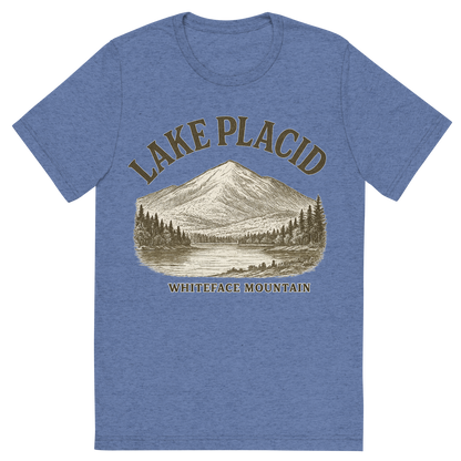 Front view of a Premium Tri-Blend Crew Neck T-Shirt in Blue showing 'A typographic, nostalgic graphic of a typographic illustration of the words 'lake placid' with a vintage line art drawing of whiteface mountain'