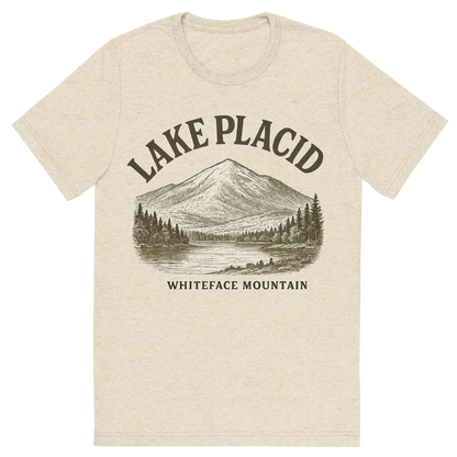 Front view of a Premium Tri-Blend Crew Neck T-Shirt in Oatmeal showing 'A typographic, nostalgic graphic of a typographic illustration of the words 'lake placid' with a vintage line art drawing of whiteface mountain'