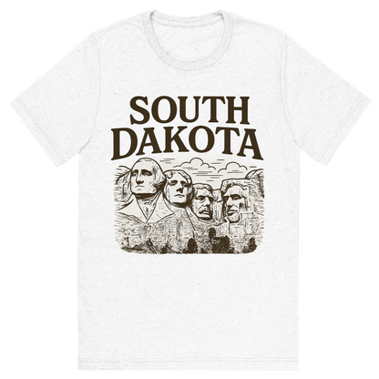 Front view of a Premium Tri-Blend Crew Neck T-Shirt in Solid White showing 'A typographic, nostalgic graphic of a typographic illustration of the words 'south dakota' with a vintage line art drawing of the presidential sculptures'