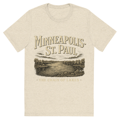 Front view of a Premium Tri-Blend Crew Neck T-Shirt in Oatmeal showing 'A typographic, nostalgic graphic of a typographic illustration of the words 'minneapolis-st. paul' with a vintage line art drawing of the chain of lakes'