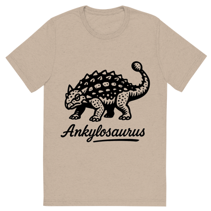 Front view of a Premium Tri-Blend Crew Neck T-Shirt in Tan showing 'A flat, neutral graphic of a bold ink drawing of an ankylosaurus with armored plates and a clubbed tail. “ankylosaurus” is inscribed below in script. ink illustration on a white background.'