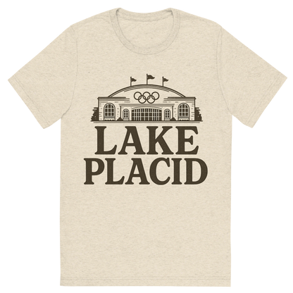 Front view of a Premium Tri-Blend Crew Neck T-Shirt in Oatmeal showing 'A typographic, nostalgic graphic of a typographic illustration of the words 'lake placid' with a vintage line art drawing of the olympic center'